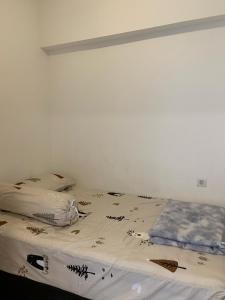 a bed in a room with a white wall at Sky House BSD D2-3A - 3 Bedroom Type in Samporo +7 photos
