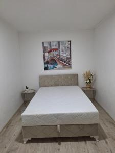 1 dormitorio blanco con 1 cama y 2 mesas en Ris kuca za odmor, en Foča