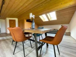 a dining room table with chairs and a vase with flowers at Gemütliche Ferienwohnung im DG am Tegernsee - Bergblick, Ruhe & ganz viel Platz in Bad Wiessee