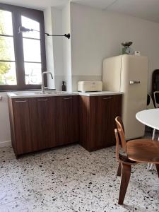 レ・ヴァンにあるPetit mas familial ardéchoisのキッチン(冷蔵庫、椅子、テーブル付)