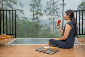 a woman sitting on the floor holding a drink at The Full Hot Spring & Resort in Kemloko-gede