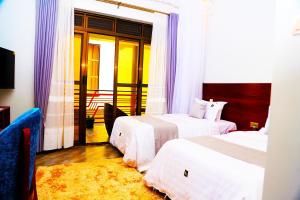 um quarto de hotel com duas camas e uma varanda em DE ALena Villas And Hotel em Mbarara