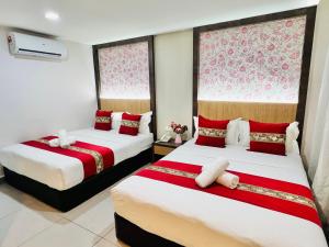Elite Hotel KL Sentral في كوالالمبور: سريرين في غرفة حمراء وبيضاء