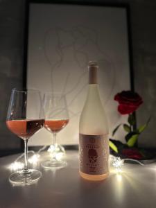 a bottle of wine and two glasses on a table at Romantic studio AxS in Floreşti