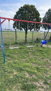 three swings in a field with a tree at Mare Resort Maggana in Xanthi