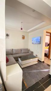 ThikaSunrise apartment next to bullys hotel的客厅里有一张沙发和一张桌子。