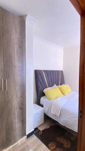 ThikaSunrise apartment next to bullys hotel的卧室里有一张床，上面放着黄色枕头