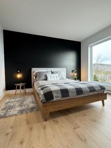 a bedroom with a large bed with a black wall at Vertigo - Fleuve & Montagnes in Les Éboulements