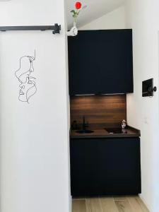 a kitchen with black cabinets and a red rose on the wall at Urban Nest in Milan