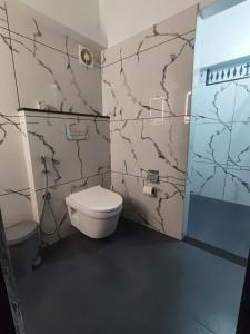 a bathroom with a white toilet in a room at Thiramizhi in Cochin +3 photos