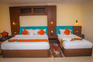 a bedroom with two beds with orange pillows at Gautam Buddha International Hotel Ltd in Gautam Buddha International Airport