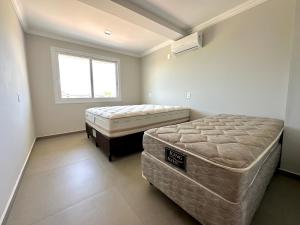 Apê Alegria - Capri Morada & Mar - Frente mar في ساو فرانسيسكو دو سول: سريرين توأم في غرفة بها نافذة