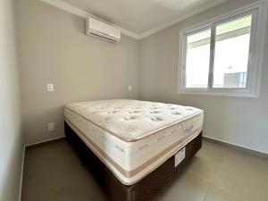 Apê Alegria - Capri Morada & Mar - Frente mar في ساو فرانسيسكو دو سول: سرير في غرفة بها نافذة