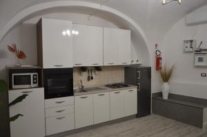a kitchen with white cabinets and a black refrigerator at MOUSUITE in Catania