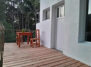 een houten terras met een tafel en stoelen op een huis bij Viento Sur in Estancia El Polomo