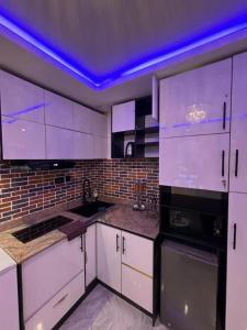a kitchen with white cabinets and a purple ceiling at Hertz Studio in Lagos