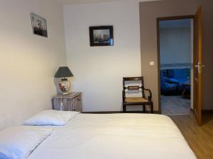 een slaapkamer met een wit bed en een stoel bij 2 Chambres dans maison typique in Beaumont-lès-Valence +5 foto's