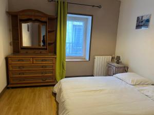 een slaapkamer met een dressoir en een bed met een spiegel bij 2 Chambres dans maison typique in Beaumont-lès-Valence