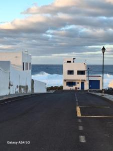 an empty street with a white building and the ocean at La Caracola in La Santa
