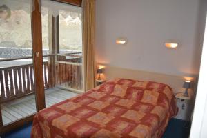 a bedroom with a bed and a balcony at l'Antre du Cerf in Villarodin-Bourget