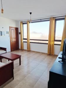 a living room with a large window and a table at La Caracola in La Santa