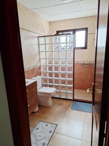 a bathroom with a toilet and a shower with glass doors at La Caracola in La Santa +14 photos