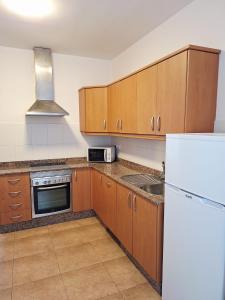 a kitchen with wooden cabinets and a white refrigerator at La Caracola in La Santa