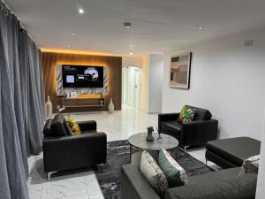 a living room with two couches and a tv at Bryanston Luxury Secure 4BR Haven in Sandton