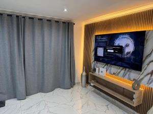 a living room with a large screen tv with curtains at Bryanston Luxury Secure 4BR Haven in Sandton