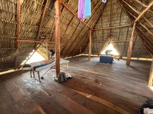 a person laying on a bed in a straw hut at Finca Buena Vida Hostel in Popoyo