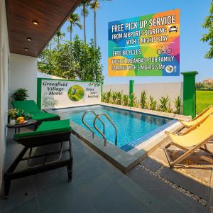 Una piscina con dos sillas y un cartel que dice servicio gratuito de recogida desde el aeropuerto. en Hoi An Private Pool Villa - Peaceful Rice Paddy Views, en Hoi An