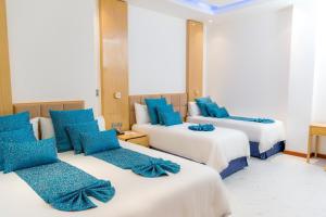 ein Hotelzimmer mit drei Betten und blauen Kissen in der Unterkunft L'ver Hotel in Somoto