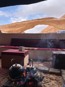 a campfire with two tea pots on top of it at Madonna Rum camp bubbles & Jeep tours in Wadi Rum