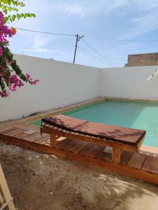 a wooden bench sitting next to a swimming pool at Keur Teranga Nianing in Nianing