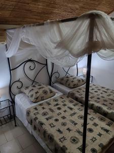 a bedroom with two beds with a canopy at Keur Teranga Nianing in Nianing +48 photos