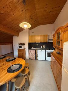 a kitchen with wooden cabinets and a wooden table and chairs at Appartement 5 pers - Draps et serviettes inclus in La Lechere