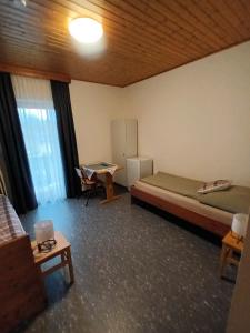 Habitación con cama, nevera y mesa. en Pension Waldfrieden, en Steinhaus am Semmering