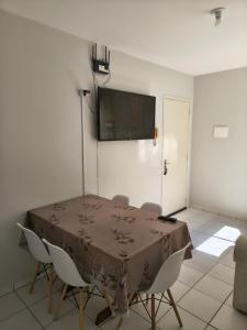 um quarto com uma mesa com cadeiras e uma televisão na parede em Apartamento aconchegante próximo a várias praias! em Palhoça