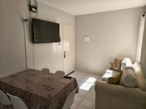 uma sala de estar com um sofá e uma televisão na parede em Apartamento aconchegante próximo a várias praias! em Palhoça