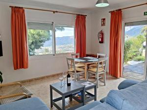een woonkamer met een tafel, stoelen en ramen bij Bungalow Los Guanches 1 in El Paso