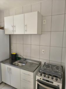 uma cozinha branca com um fogão e um lavatório em Apartamento aconchegante próximo a várias praias! em Palhoça