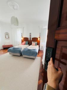 Portas Residence, Ponta Delgada في بونتا ديلغادا: شخص يفتح باب غرفة نوم بها سريرين