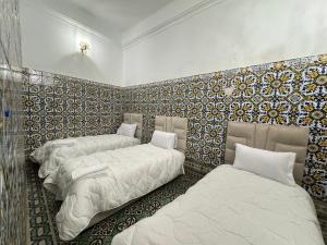 três camas em um quarto com azulejos na parede em Riad Roqia em Rabat
