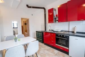 a kitchen with red cabinets and a table and chairs at Studio apartman LuG in Ravna Gora