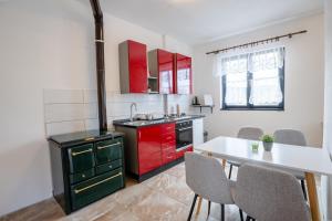 a kitchen with red cabinets and a white table at Studio apartman LuG in Ravna Gora +2 photos