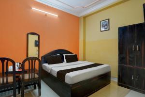 a bedroom with a bed with an orange wall at Hotel O Durgapuri Metro Station Lucknow Formerly Pal Awadh in Bādshāhnagar