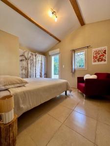 a bedroom with a large bed and a red chair at La maison des Oiseaux in Trans-en-Provence