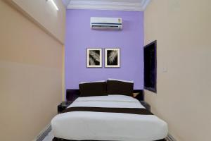 a bedroom with a large bed with purple walls at Hotel O Durgapuri Metro Station Lucknow Formerly Pal Awadh in Bādshāhnagar