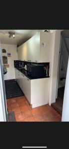a kitchen with white cabinets and a black microwave at The Old Hanging Gate Inn in Madeley