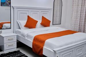 a bedroom with a bed with an orange blanket and a mirror at Darflings Haven-Diani in Ukunda +12 photos